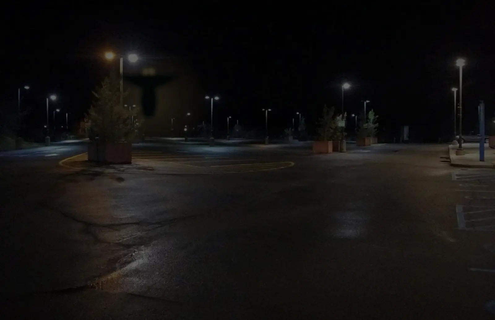 Lot camera still, Ronkonkoma: a winged figure at the edge of the sodium light